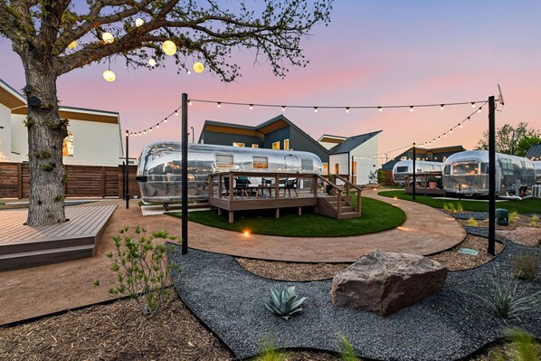A residential area with multiple trailers, a deck with outdoor furniture, and a landscaped garden. - Refined Casita Near Medical District, Parking Included (Fort Worth)