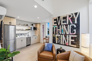 A modern kitchen with stainless steel appliances and a dining area with a large abstract painting. - Experience Cowtown Charm, Casita Near TCU & Stockyards (Fort Worth)