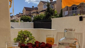A table with a bowl of strawberries, a glass of coffee, and a water bottle. - Casa Kate La Zenia (Orihuela)