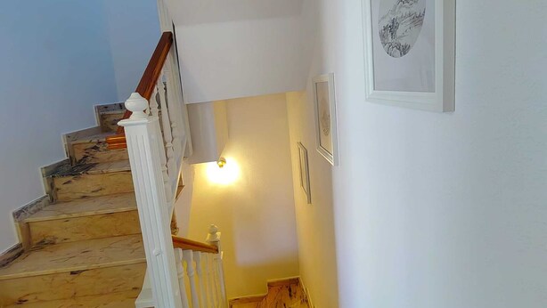 A staircase with wooden steps leading to a landing with a light fixture. - Casa Kate La Zenia (Orihuela)