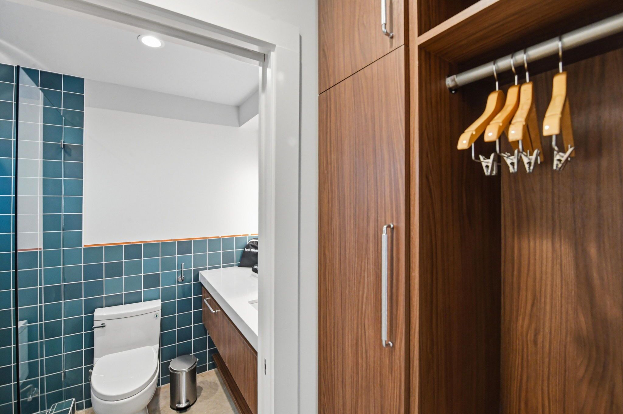 A modern bathroom with a toilet, sink, and wooden cabinet.