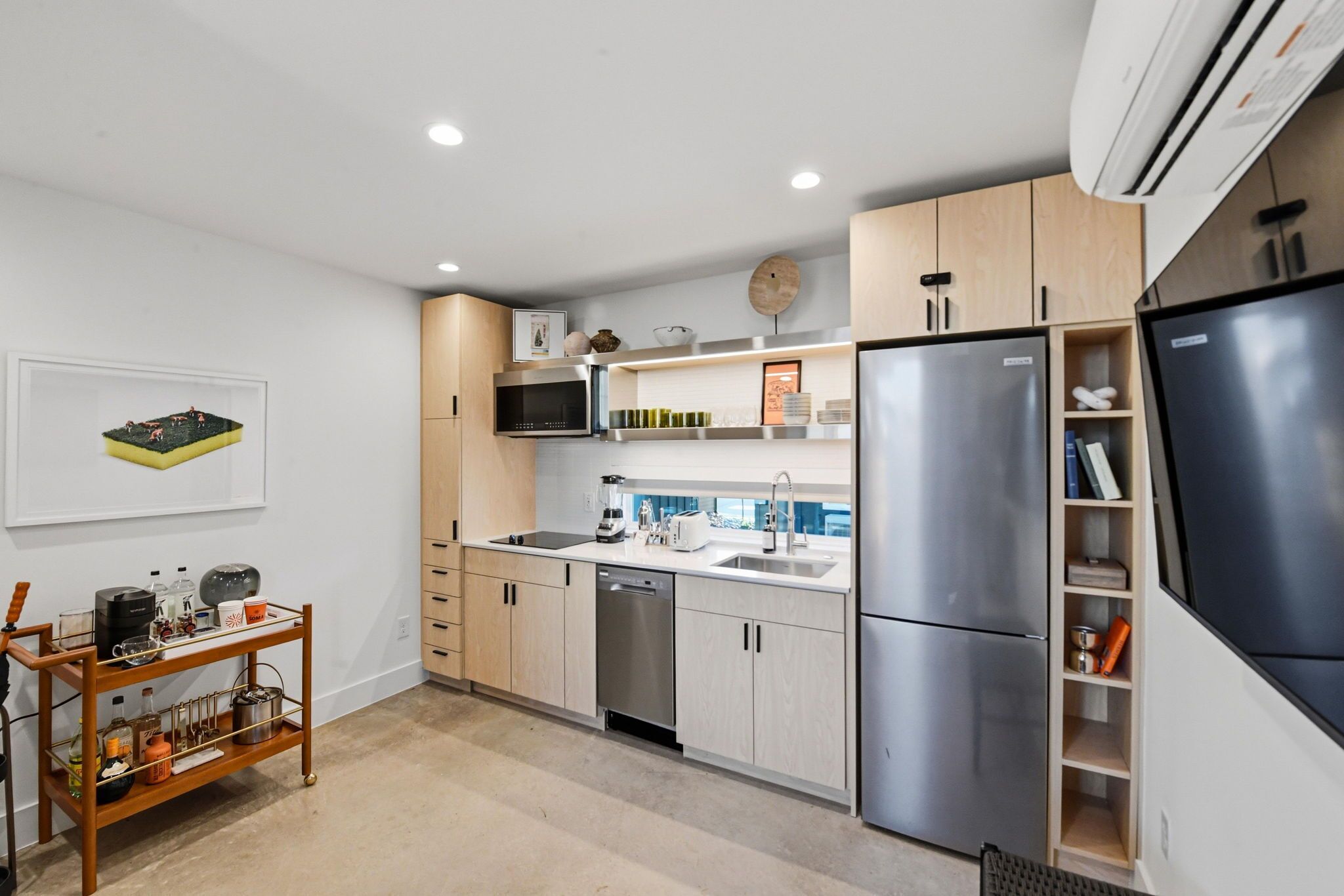 A modern kitchen with stainless steel appliances, wooden cabinets, and a built-in dishwasher.