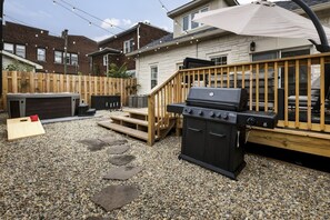 A backyard with a barbecue grill, wooden deck, and a hot tub. - The Social House - 7BR, Hot Tub & Pool Table (Indianapolis)