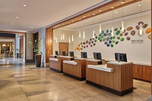 Ein Empfangsbereich mit hölzernen Empfangstresen, einer Wand aus bunten Steinen und einem Schild für Westin Hotels & Resorts.