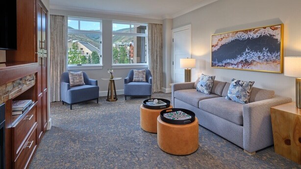 A hotel room with a sofa, two armchairs, a TV, a painting, and a view of buildings through the window. - 2 Bedroom Villa Westin Riverfront Mountain Resort (Avon)