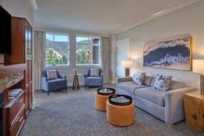 A hotel room with a sofa, two armchairs, a TV, a painting, and a view of buildings through the window. - 2 Bedroom Villa Westin Riverfront Mountain Resort (Avon)