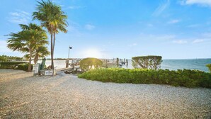 Propiedad privada con un sendero de grava, palmeras, un muelle y vista al mar.
