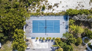 Eine Vogelperspektive zeigt einen Tennisplatz, der von üppigem Grün umgeben ist.