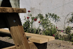 A wooden bench with a concrete wall in the background.