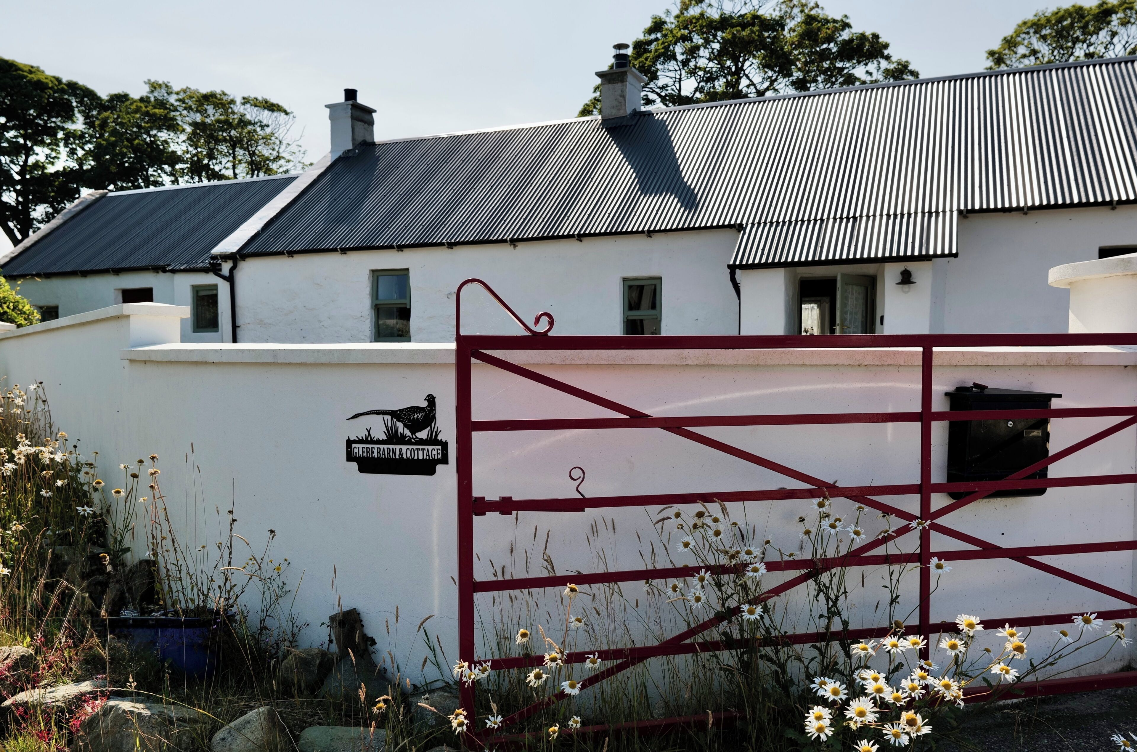 A white building with a metal roof and a red gate.