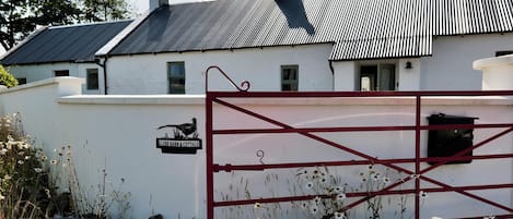 A white building with a metal roof and a red gate.
