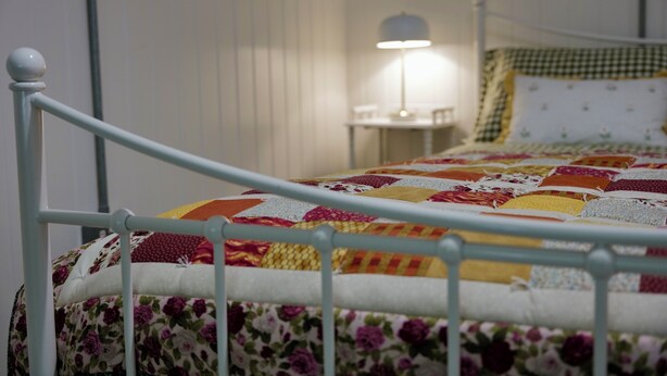 A bed with a floral-patterned bedspread and a metal headboard. - Charming Irish Cottage Offering Peace, Comfort and Stunning Lough View (Londonderry)