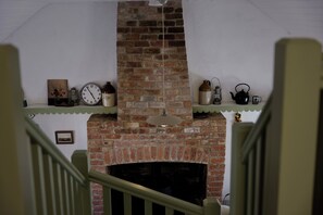 A brick fireplace with a clock and various decorative items on shelves above it. - Charming Irish Cottage Offering Peace, Comfort and Stunning Lough View (Londonderry)