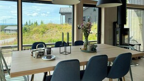 Un comedor con una mesa grande, sillas, un florero con flores y una chimenea.