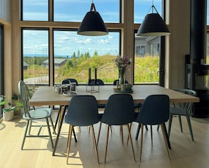A dining area with a large table, chairs, and a view through large windows.