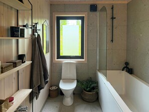 Une salle de bain moderne équipée de toilettes, d’une douche et d’une fenêtre qui laisse entrer la lumière naturelle.