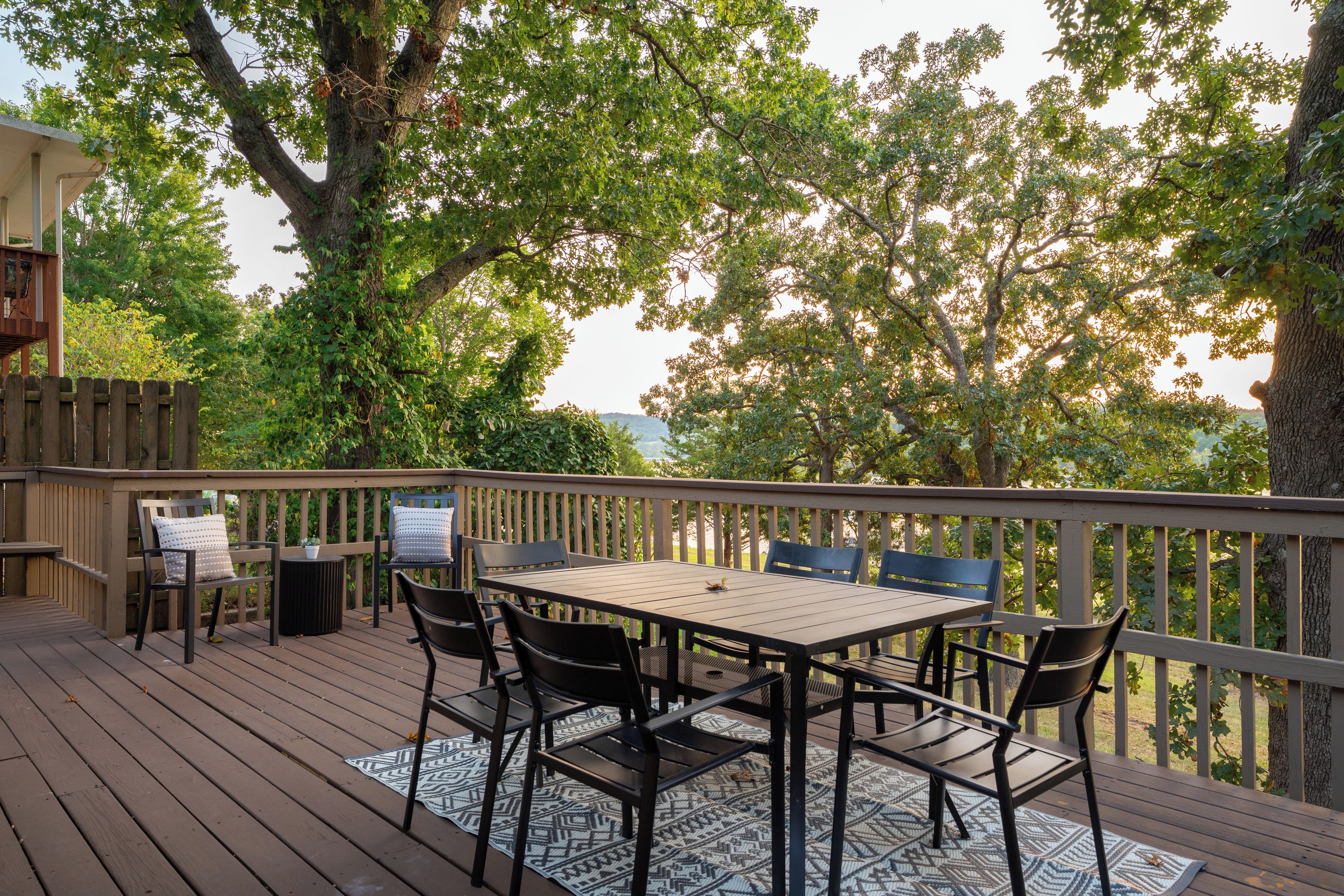 A wooden deck with a table and chairs, surrounded by trees.