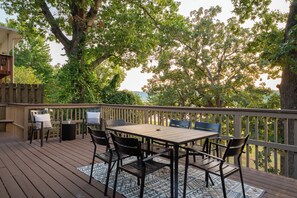 Eine Holzterrasse mit Tisch und Stühlen, umgeben von Bäumen.