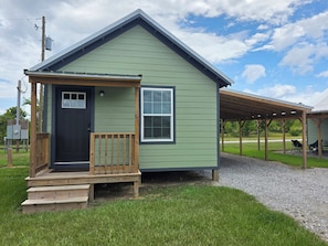 A small, single-story building with a front porch and a covered outdoor seating area.