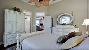 A bedroom with a large bed, a dresser, a mirror, and a ceiling fan. - Walk To Beach | Heated Lagoon Pool, on Anna Maria! (Holmes Beach)