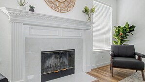 A living room with a white fireplace, a black leather chair, and a wooden floor. - Family Reunion HQ, Sleeps 14 Frisco, Hot Tub (Frisco)