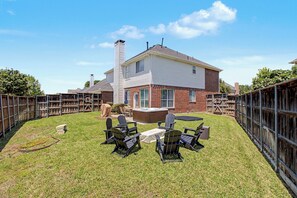 Ein Garten mit Whirlpool, Sitzgelegenheit im Freien und einem umzäunten Bereich.