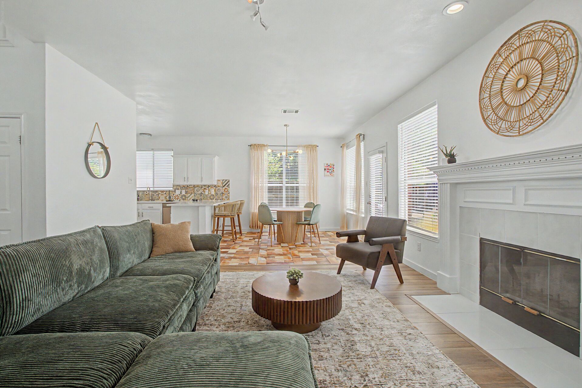 A living room with a fireplace, a dining area with a table and chairs, and a kitchen in the background.