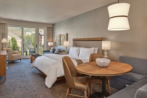 Ett hotellrum med en säng, ett runt matbord, en soffa och utsikt genom en glasdörr.