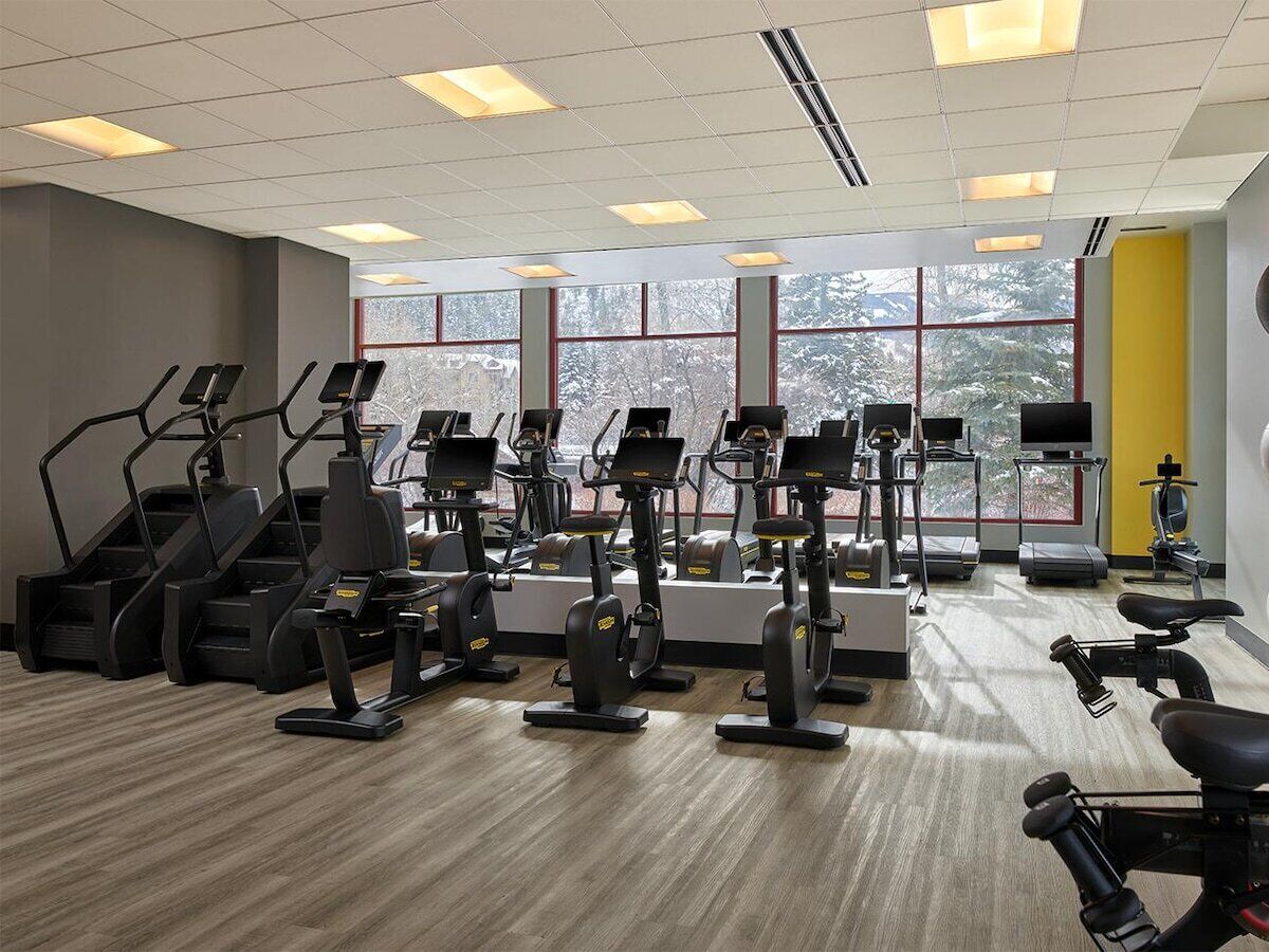 Un gimnasio con cintas de correr, elípticas y equipo de pesas.