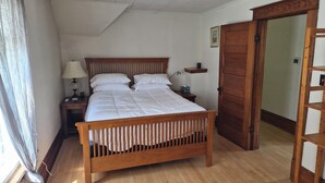 Ein Schlafzimmer mit einem hölzernen Bett, einem Nachttisch, einer Nachttischlampe, einem Deckenventilator und einer Holztür.