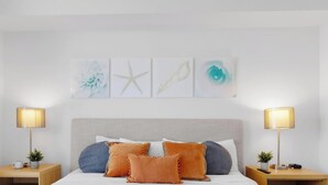 A bedroom with a bed, two bedside tables, a nightstand, and wall art. - New! Sunset Suite 2BR - Bay View Fitness Center (Hallandale Beach)