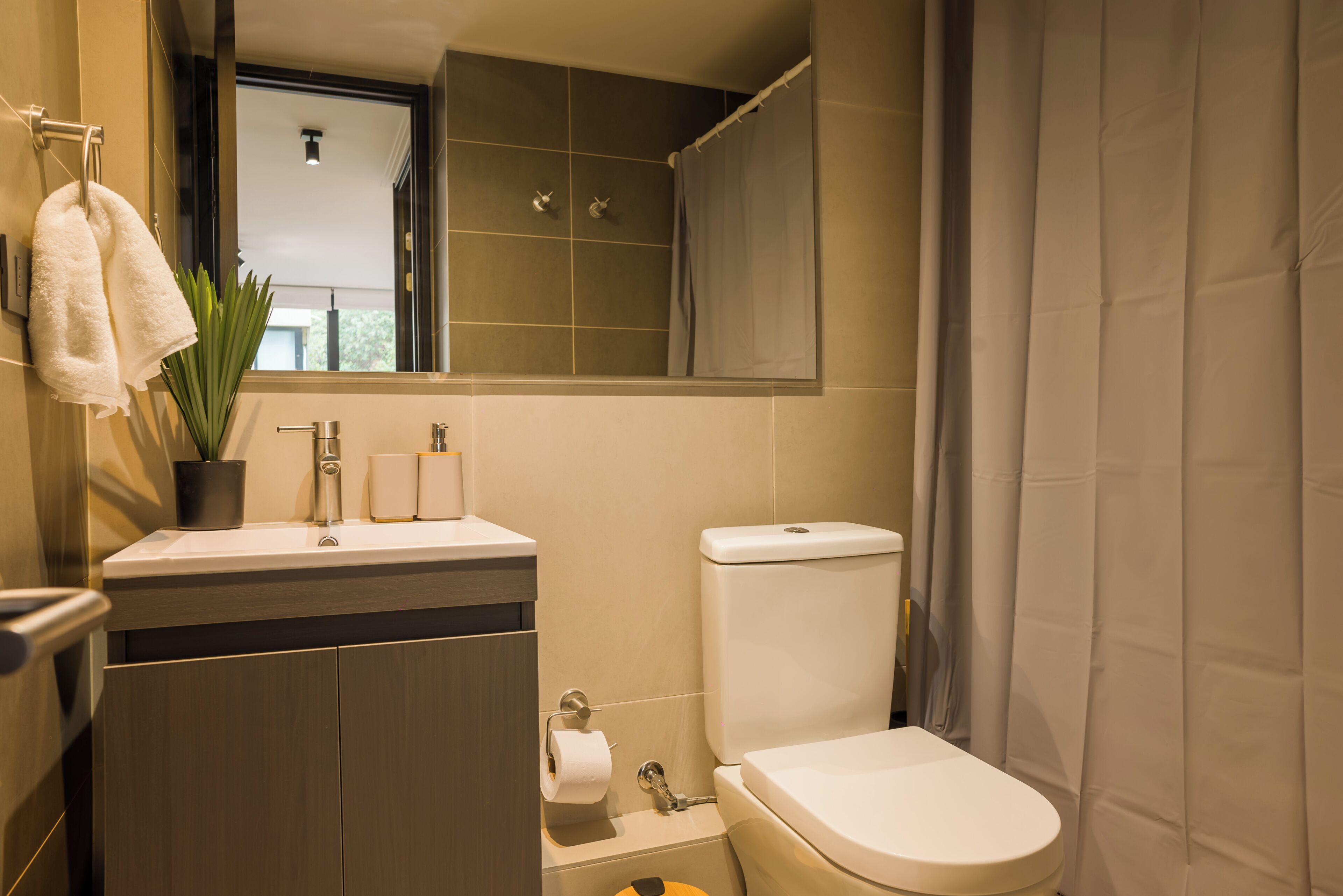 Une salle de bain moderne équipée de toilettes, d’un lavabo et d’un miroir placé au-dessus du lavabo.