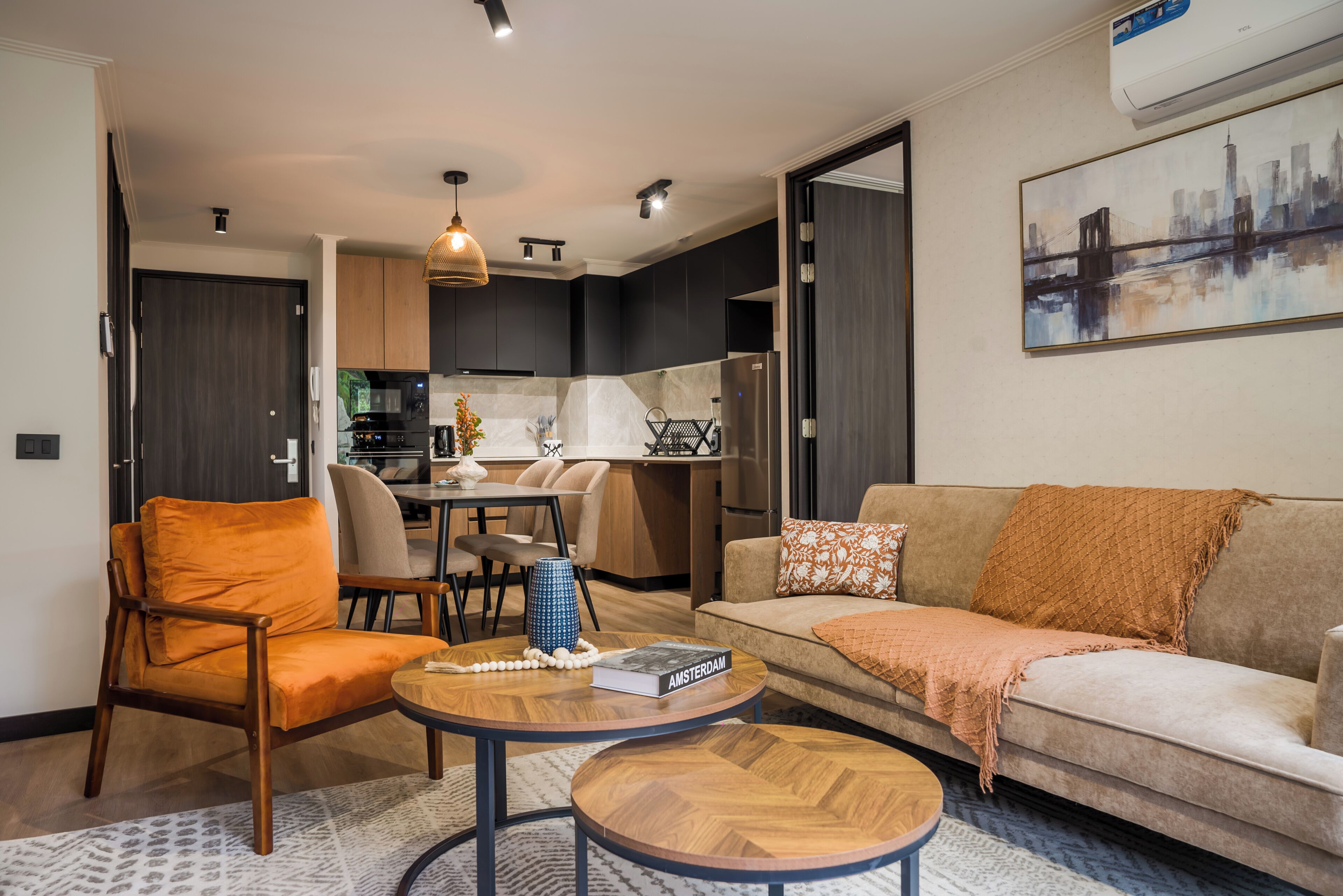 A modern living room with a sofa, armchair, coffee table, and a dining area with chairs and a table.