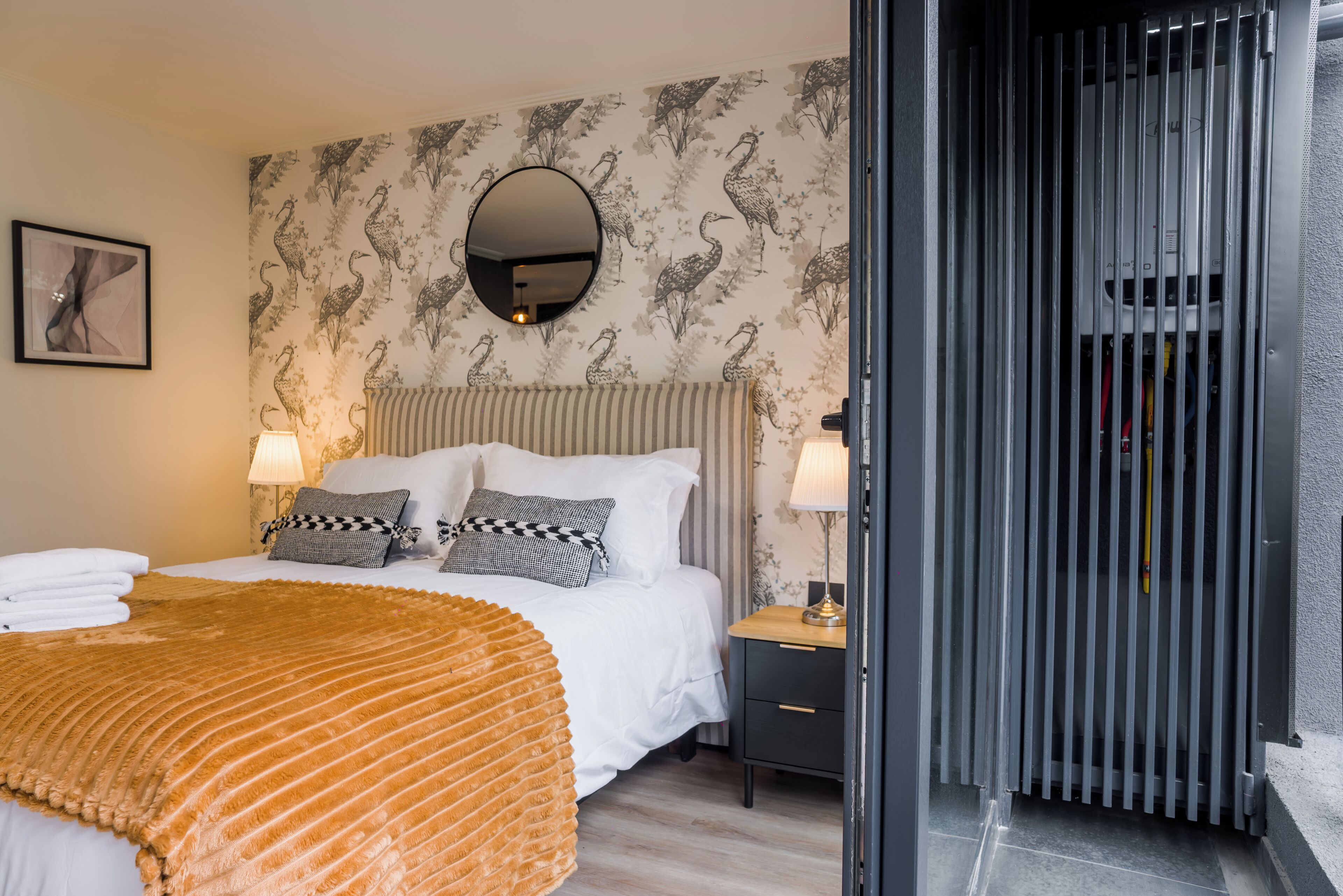 A hotel room with a bed, two bedside lamps, a nightstand, and a mirror on the wall.