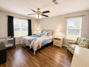 A bedroom with a bed, bedside tables, a chair, a ceiling fan, and windows. - Ortega Oasis- New Listing in Navarre, 10 minutes to Navarre Beach! (Navarre)