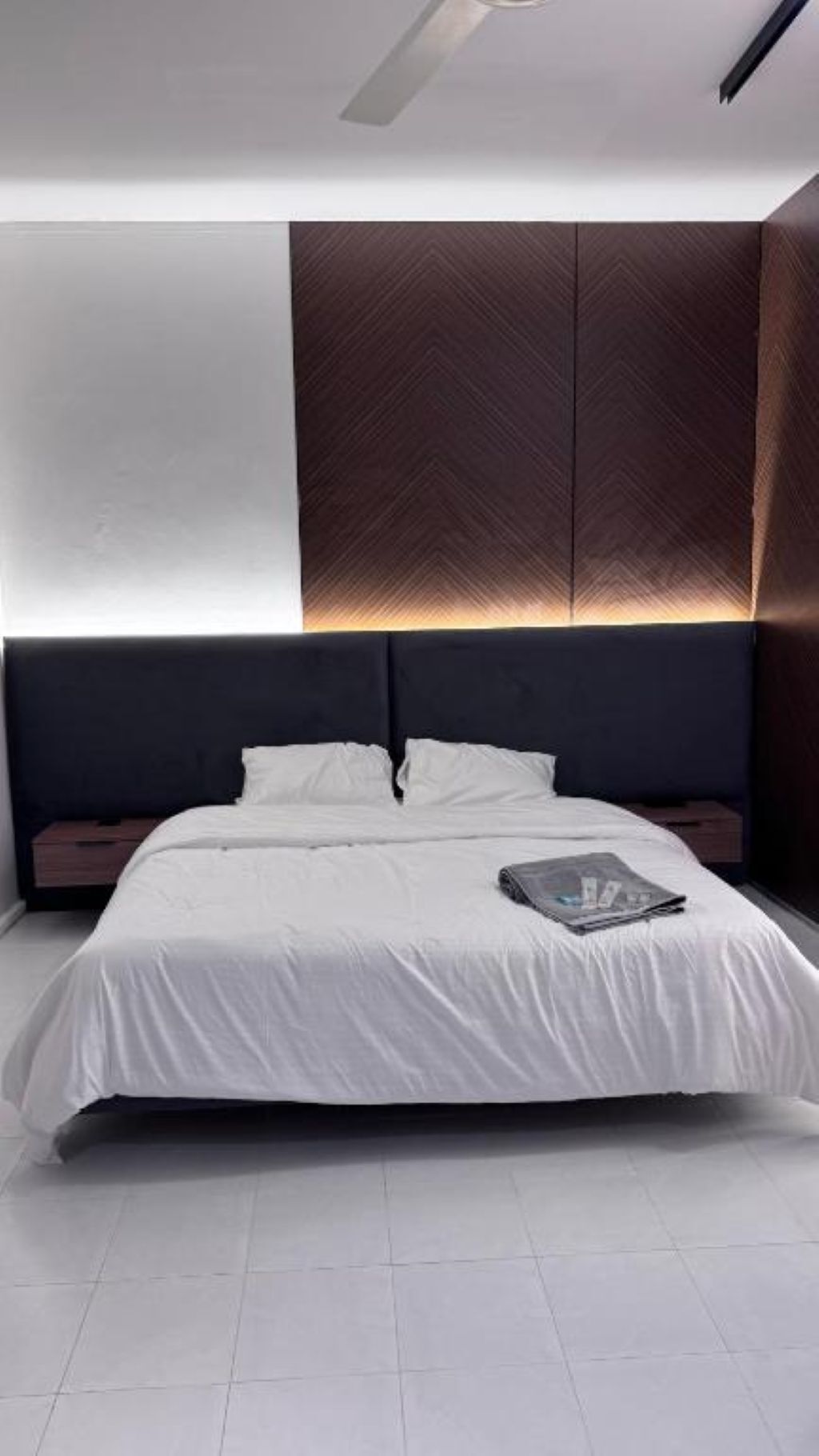 A modern bedroom with a large bed, a headboard with built-in lighting, and a nightstand.