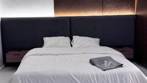 Un dormitorio moderno con una cama grande, cabecera con iluminación integrada y una mesita de noche.