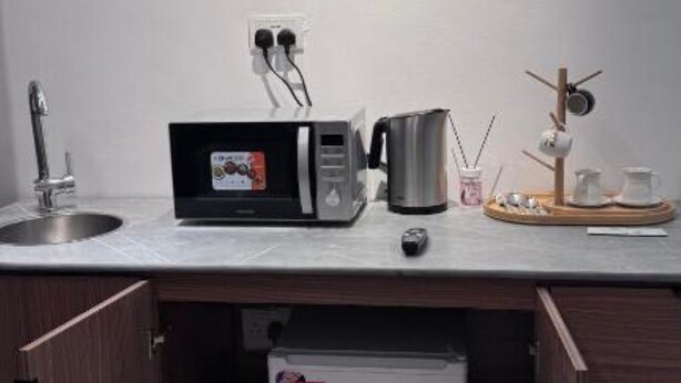 Una kitchenette compacta con microondas, hervidor y un refrigerador pequeño.