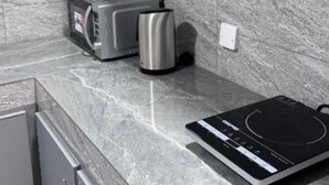 Una cocina con armarios grises, un tostador, un hervidor y una cocina de inducción.