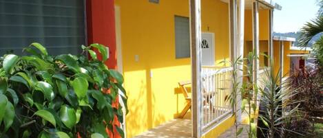 A yellow building with a covered outdoor seating area and a large window.