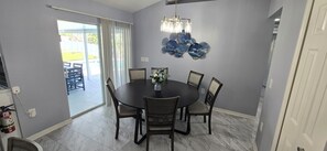 A dining area with a round table, chairs, a vase with flowers, and a decorative wall piece.