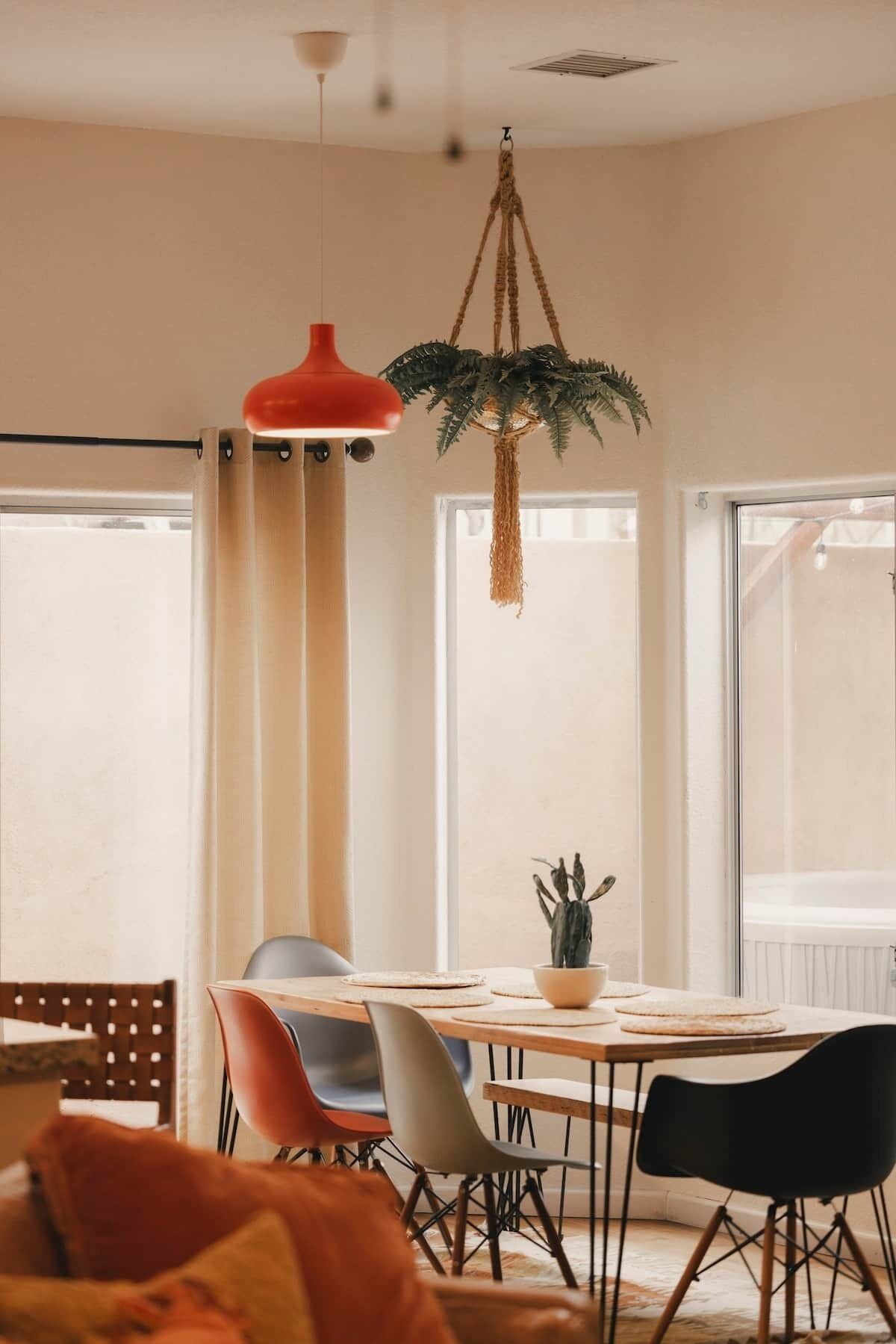 A dining area with a wooden table, chairs, and a hanging plant.