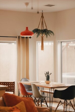 Un comedor con una mesa de madera, sillas y una planta colgante.