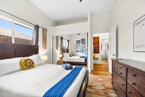 Ein Hotelzimmer mit einem großen Bett, einem Schminktisch, einem Spiegel und Blick ins Freie.
