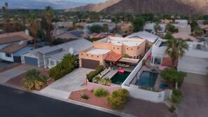 Ein Wohngebiet mit einem Haus, das einen Pool, eine Garage und einen gepflegten Garten hat.