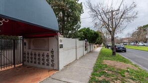 A building with a numbered address, a sidewalk, and parked cars. - The Courtyard on Buckley (Moonee Ponds)