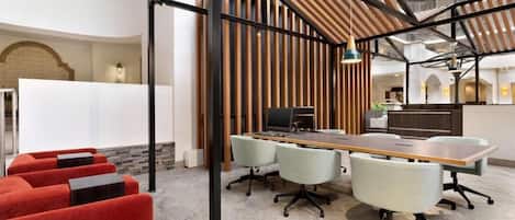 A modern conference room with a long table, multiple chairs, and a red seating area.