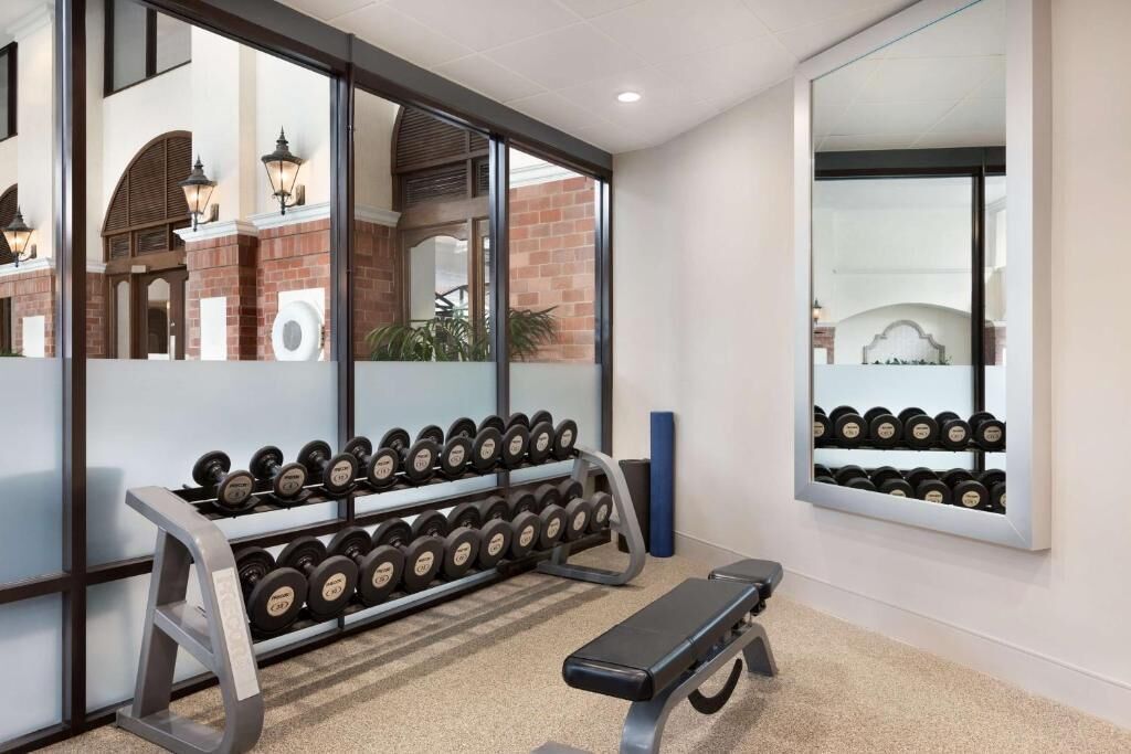 Un gimnasio con banco, mancuernas y espejo.