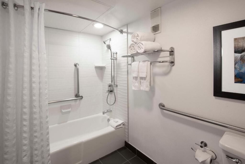 Uma casa de banho moderna com banheira, chuveiro, sanita e porta-toalhas.