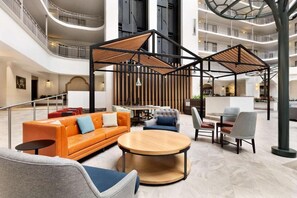 Un hall espacioso con una zona de estar central, varios pisos con balcones y un diseño arquitectónico moderno.